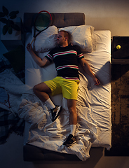 Image showing Top view of young professional tennis player sleeping at his bedroom in sportwear with racket