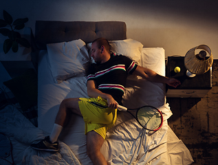 Image showing Top view of young professional tennis player sleeping at his bedroom in sportwear with racket