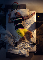 Image showing Top view of young professional tennis player sleeping at his bedroom in sportwear with racket