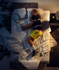 Image showing Top view of young professional tennis player sleeping at his bedroom in sportwear with racket