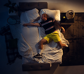 Image showing Top view of young professional tennis player sleeping at his bedroom in sportwear with racket