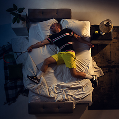 Image showing Top view of young professional tennis player sleeping at his bedroom in sportwear with racket