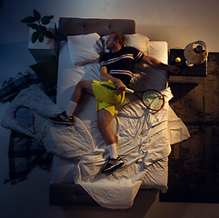 Image showing Top view of young professional tennis player sleeping at his bedroom in sportwear with racket