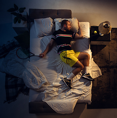 Image showing Top view of young professional tennis player sleeping at his bedroom in sportwear with racket