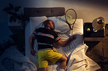 Image showing Top view of young professional tennis player sleeping at his bedroom in sportwear with racket