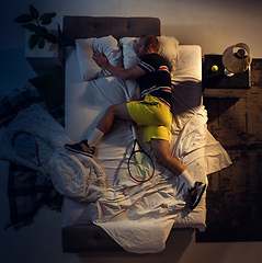 Image showing Top view of young professional tennis player sleeping at his bedroom in sportwear with racket