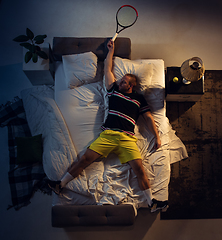 Image showing Top view of young professional tennis player sleeping at his bedroom in sportwear with racket