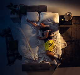 Image showing Top view of young professional tennis player sleeping at his bedroom in sportwear with racket