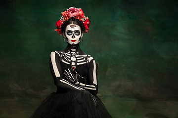 Image showing Young girl in the image of Santa Muerte, Saint death or Sugar skull with bright make-up. Portrait isolated on studio background.