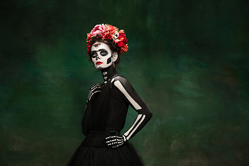 Image showing Young girl in the image of Santa Muerte, Saint death or Sugar skull with bright make-up. Portrait isolated on studio background.