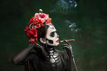 Image showing Young girl in the image of Santa Muerte, Saint death or Sugar skull with bright make-up. Portrait isolated on studio background.
