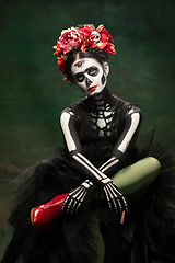 Image showing Young girl in the image of Santa Muerte, Saint death or Sugar skull with bright make-up. Portrait isolated on studio background.