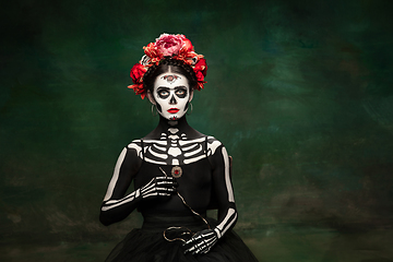 Image showing Young girl in the image of Santa Muerte, Saint death or Sugar skull with bright make-up. Portrait isolated on studio background.