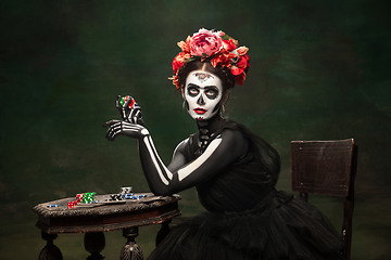 Image showing Young girl in the image of Santa Muerte, Saint death or Sugar skull with bright make-up. Portrait isolated on studio background.