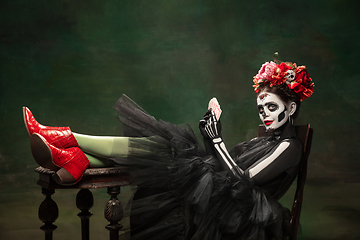 Image showing Young girl in the image of Santa Muerte, Saint death or Sugar skull with bright make-up. Portrait isolated on studio background.