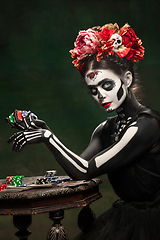 Image showing Young girl in the image of Santa Muerte, Saint death or Sugar skull with bright make-up. Portrait isolated on studio background.