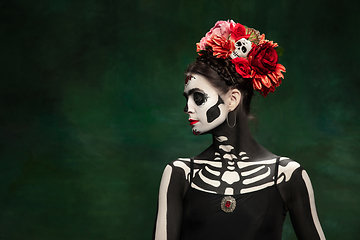 Image showing Young girl in the image of Santa Muerte, Saint death or Sugar skull with bright make-up. Portrait isolated on studio background.