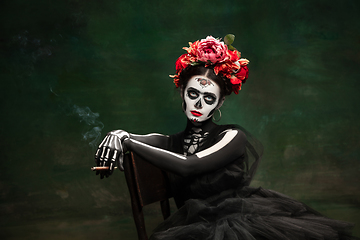 Image showing Young girl in the image of Santa Muerte, Saint death or Sugar skull with bright make-up. Portrait isolated on studio background.