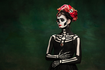 Image showing Young girl in the image of Santa Muerte, Saint death or Sugar skull with bright make-up. Portrait isolated on studio background.