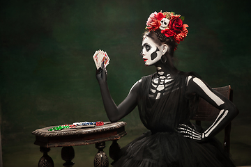 Image showing Young girl in the image of Santa Muerte, Saint death or Sugar skull with bright make-up. Portrait isolated on studio background.