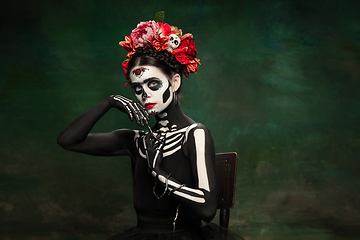 Image showing Young girl in the image of Santa Muerte, Saint death or Sugar skull with bright make-up. Portrait isolated on studio background.