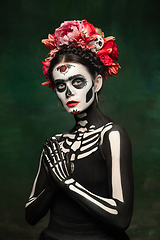 Image showing Young girl in the image of Santa Muerte, Saint death or Sugar skull with bright make-up. Portrait isolated on studio background.