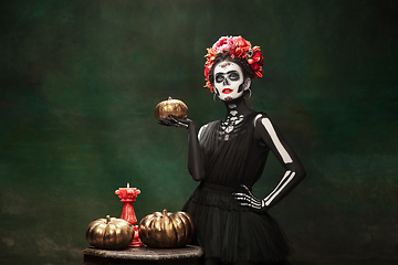 Image showing Young girl in the image of Santa Muerte, Saint death or Sugar skull with bright make-up. Portrait isolated on studio background.