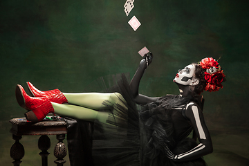 Image showing Young girl in the image of Santa Muerte, Saint death or Sugar skull with bright make-up. Portrait isolated on studio background.