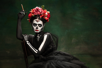 Image showing Young girl in the image of Santa Muerte, Saint death or Sugar skull with bright make-up. Portrait isolated on studio background.