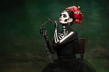 Image showing Young girl in the image of Santa Muerte, Saint death or Sugar skull with bright make-up. Portrait isolated on studio background.