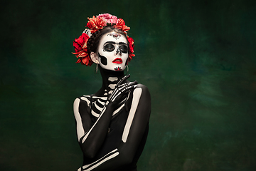 Image showing Young girl in the image of Santa Muerte, Saint death or Sugar skull with bright make-up. Portrait isolated on studio background.