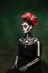 Image showing Young girl in the image of Santa Muerte, Saint death or Sugar skull with bright make-up. Portrait isolated on studio background.