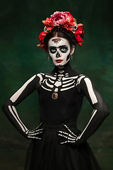 Image showing Young girl in the image of Santa Muerte, Saint death or Sugar skull with bright make-up. Portrait isolated on studio background.