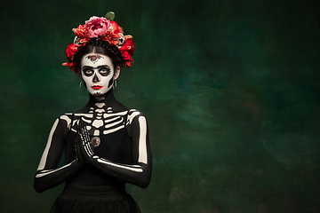 Image showing Young girl in the image of Santa Muerte, Saint death or Sugar skull with bright make-up. Portrait isolated on studio background.