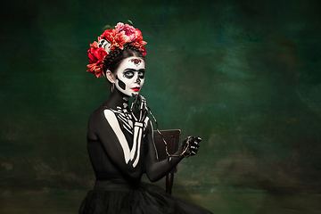 Image showing Young girl in the image of Santa Muerte, Saint death or Sugar skull with bright make-up. Portrait isolated on studio background.