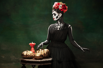 Image showing Young girl in the image of Santa Muerte, Saint death or Sugar skull with bright make-up. Portrait isolated on studio background.