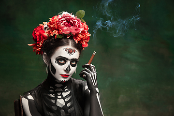 Image showing Young girl in the image of Santa Muerte, Saint death or Sugar skull with bright make-up. Portrait isolated on studio background.