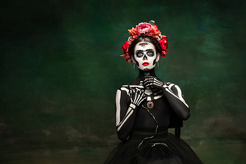 Image showing Young girl in the image of Santa Muerte, Saint death or Sugar skull with bright make-up. Portrait isolated on studio background.