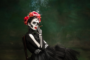 Image showing Young girl in the image of Santa Muerte, Saint death or Sugar skull with bright make-up. Portrait isolated on studio background.