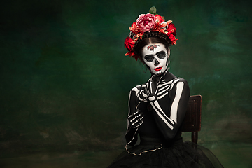 Image showing Young girl in the image of Santa Muerte, Saint death or Sugar skull with bright make-up. Portrait isolated on studio background.