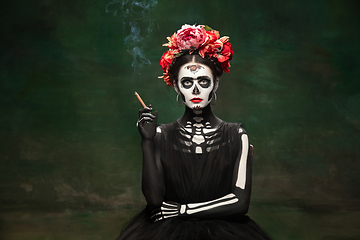 Image showing Young girl in the image of Santa Muerte, Saint death or Sugar skull with bright make-up. Portrait isolated on studio background.