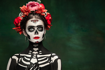 Image showing Young girl in the image of Santa Muerte, Saint death or Sugar skull with bright make-up. Portrait isolated on studio background.