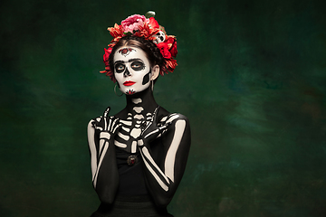 Image showing Young girl in the image of Santa Muerte, Saint death or Sugar skull with bright make-up. Portrait isolated on studio background.