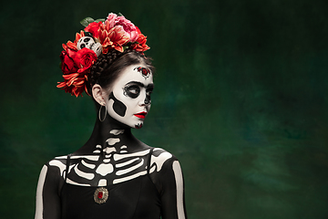 Image showing Young girl in the image of Santa Muerte, Saint death or Sugar skull with bright make-up. Portrait isolated on studio background.