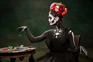 Image showing Young girl in the image of Santa Muerte, Saint death or Sugar skull with bright make-up. Portrait isolated on studio background.