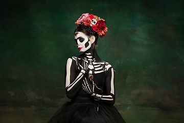 Image showing Young girl in the image of Santa Muerte, Saint death or Sugar skull with bright make-up. Portrait isolated on studio background.