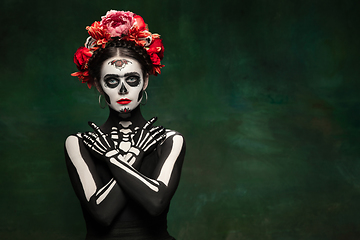 Image showing Young girl in the image of Santa Muerte, Saint death or Sugar skull with bright make-up. Portrait isolated on studio background.