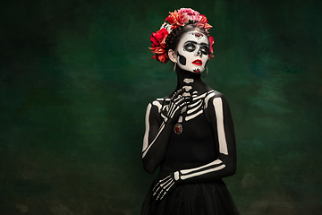 Image showing Young girl in the image of Santa Muerte, Saint death or Sugar skull with bright make-up. Portrait isolated on studio background.