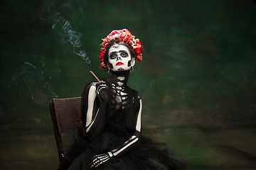 Image showing Young girl in the image of Santa Muerte, Saint death or Sugar skull with bright make-up. Portrait isolated on studio background.