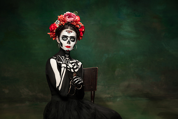 Image showing Young girl in the image of Santa Muerte, Saint death or Sugar skull with bright make-up. Portrait isolated on studio background.